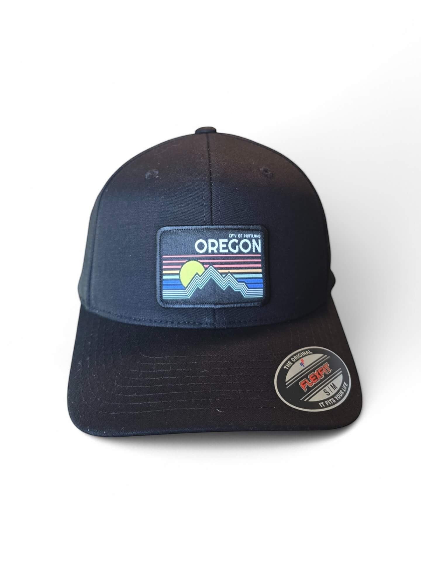 Moove Headwear black baseball cap with a colorful "Oregon" patch featuring mountains and a sunset. Flexfit technology.