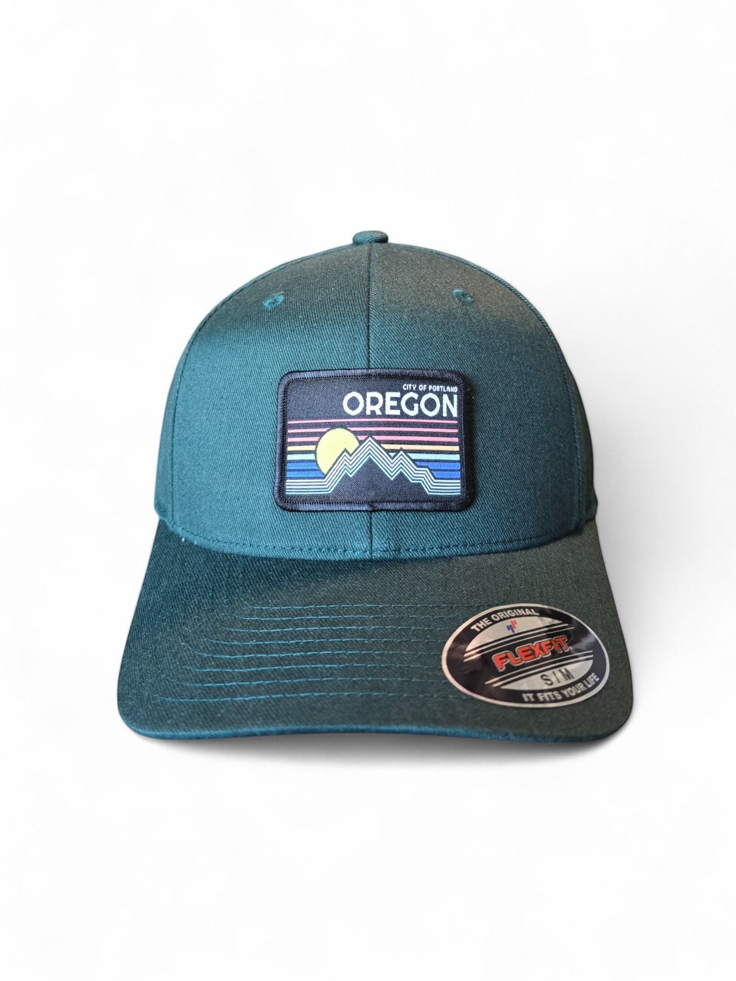 Moove Headwear Oregon baseball cap in teal with a retro mountain and sun patch. Features Flexfit technology.
