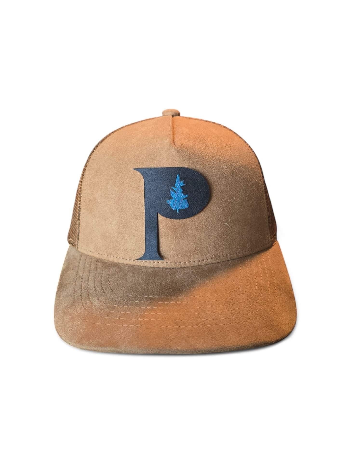 Moove Headwear tan suede trucker hat with a dark blue "P" logo and blue tree detail, mesh back, adjustable snapback.