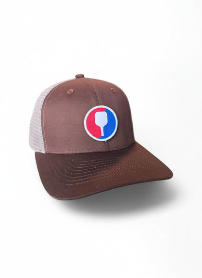 Moove Headwear brown trucker hat with mesh back and pickleball paddle patch. Adjustable snapback.