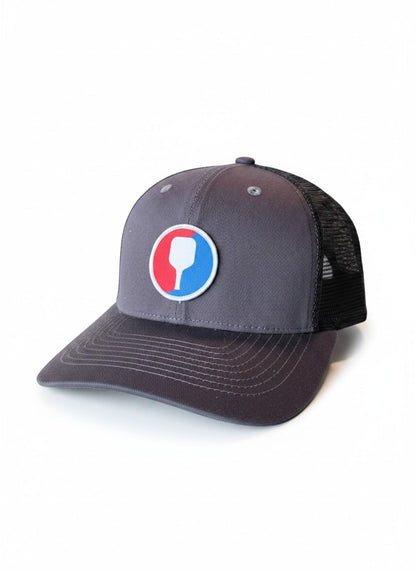 Moove Headwear grey trucker hat with pickleball paddle patch and mesh back. Adjustable snapback closure.