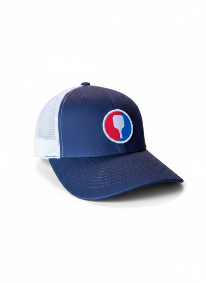 Moove Headwear navy blue trucker hat with white mesh back and a circular pickleball paddle patch.