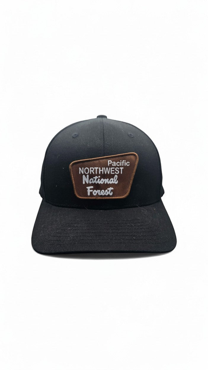 Moove Headwear black baseball cap with a brown patch featuring "Pacific Northwest National Forest" text. Unisex Flexfit style.