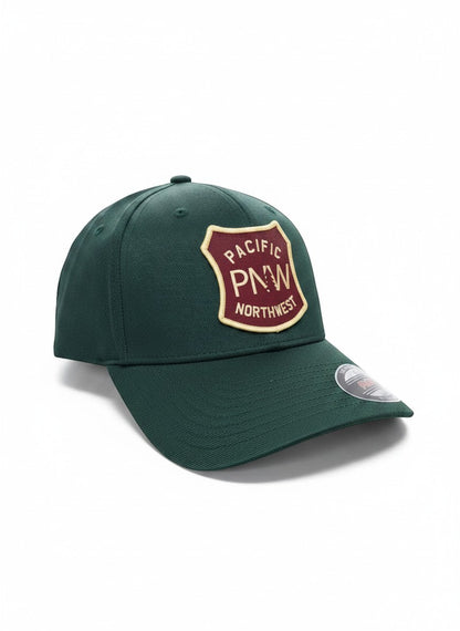 Moove Headwear dark green baseball cap with a maroon and tan PNW Pacific Northwest shield patch.
