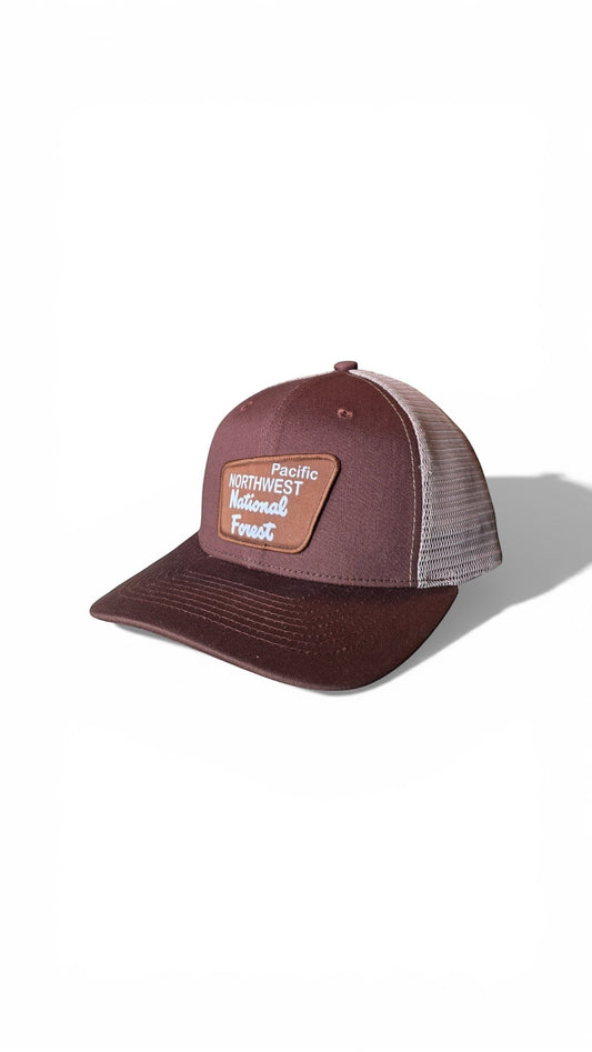 Moove Headwear brown trucker hat with mesh back and Pacific Northwest National Forest patch. Adjustable snapback for hiking and camping.