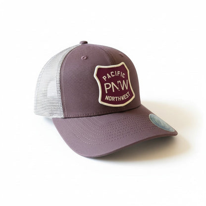 Moove Headwear Pacific Northwest trucker hat in plum with a mesh back and a shield-shaped patch with PNW graphic.
