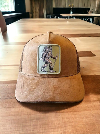 Moove Headwear brown suede trucker hat with Sasquatch hiker patch and mesh back, adjustable snapback.