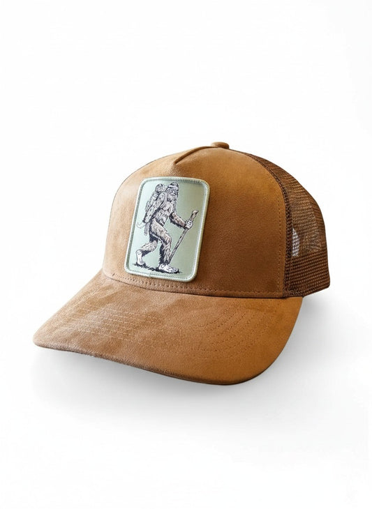 Moove Headwear brown suede trucker hat with Sasquatch hiker patch and mesh back. Adjustable snapback.