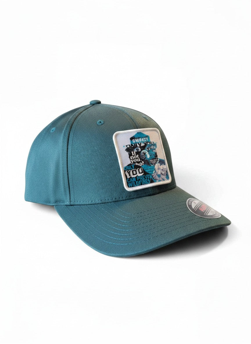 Moove Headwear dark teal fitted hat with Smokey Bear wildfire prevention patch. Structured crown, mid-profile.