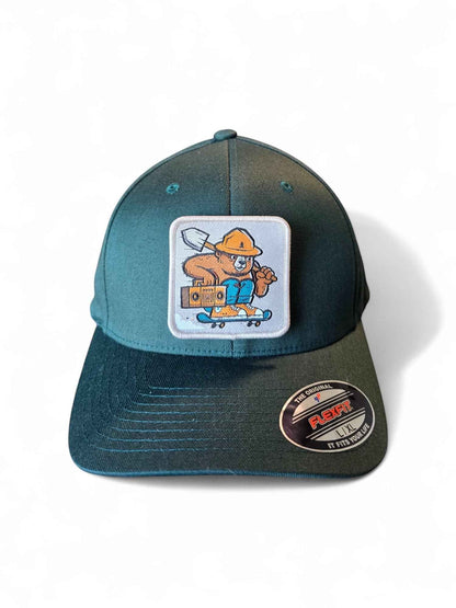 Moove Headwear teal Flexfit hat with Smokey Bear skateboarding patch. Features embroidered Smokey Bear with shovel and boombox.