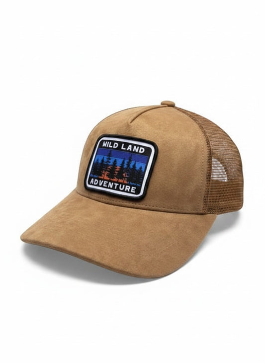 Moove Headwear tan suede trucker hat with embroidered "Wild Land Adventure" patch and mesh back panels.