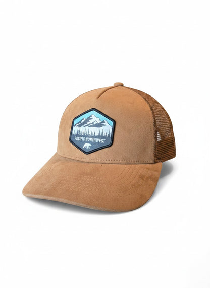 Moove Headwear tan suede trucker hat with mesh back and embroidered Pacific Northwest mountain and forest patch.