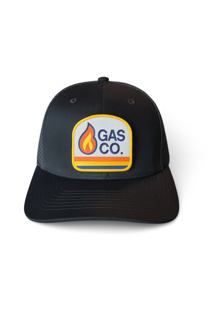 All black retro trucker hat with classic Gas Co. flame patch, mesh back, and snapback fit